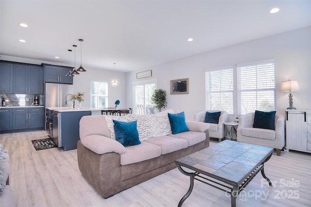 living room with a notable chandelier, recessed lighting, and light wood-style floors