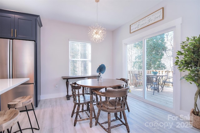 dining space featuring a chandelier, light wood finished floors, a wealth of natural light, and baseboards