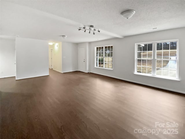 empty room with baseboards, dark wood finished floors, and a textured ceiling