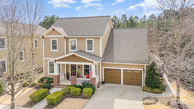 view of front of house with an attached garage, driveway, a porch, and a shingled roof