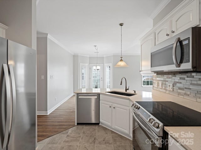 kitchen with stainless steel appliances, backsplash, white cabinetry, a sink, and a peninsula