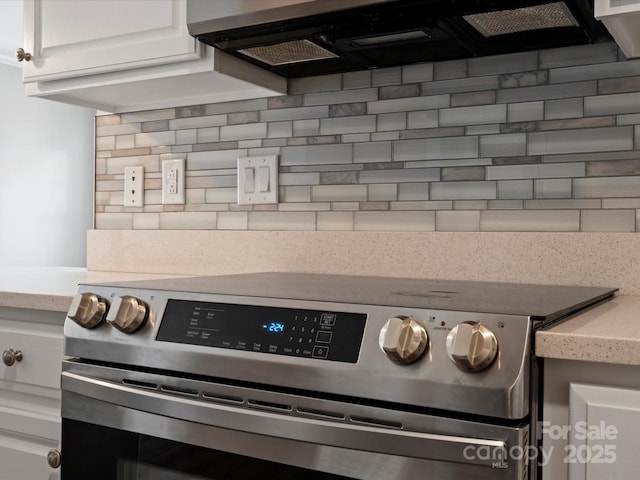 room details featuring light stone countertops, decorative backsplash, white cabinets, and stainless steel electric stove