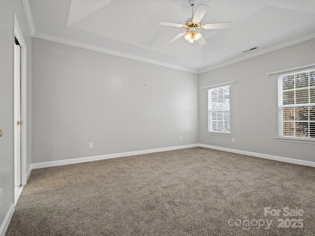 empty room featuring carpet floors, a tray ceiling, a wealth of natural light, and ornamental molding