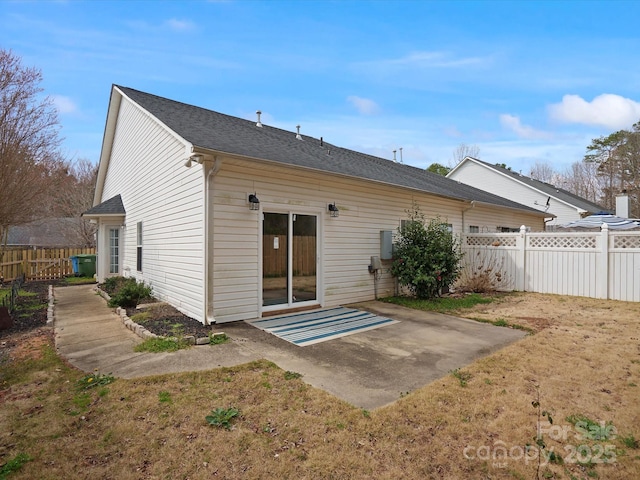 back of house with roof with shingles, a patio, and fence