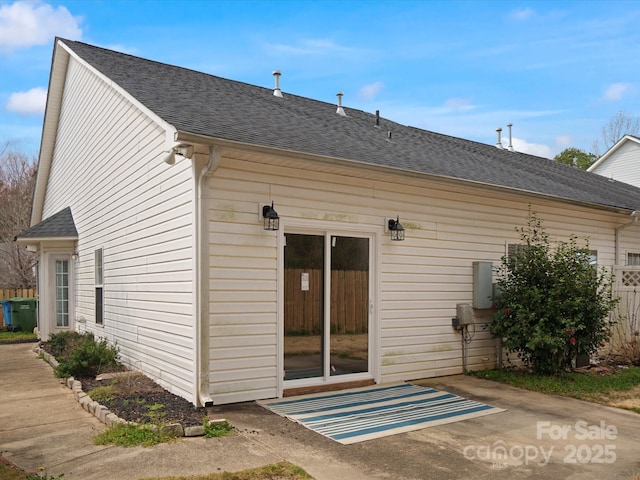 back of property with roof with shingles and fence