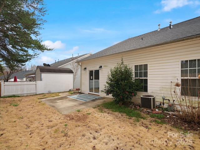 back of house with roof with shingles, a patio, central air condition unit, fence, and an outdoor structure