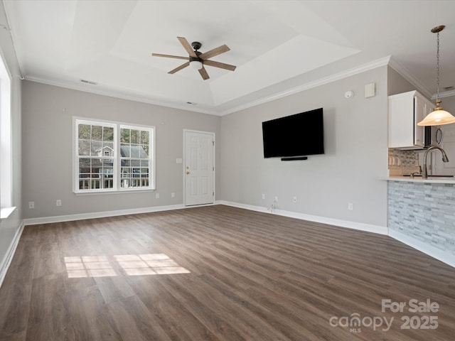 unfurnished living room featuring baseboards, a tray ceiling, and dark wood-style flooring