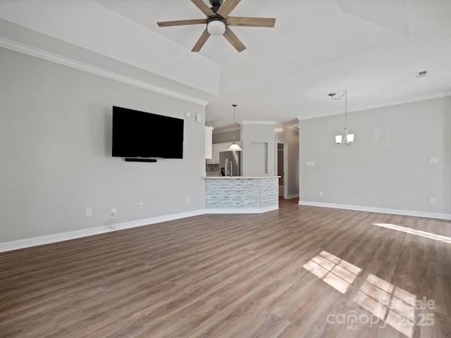 unfurnished living room with ceiling fan with notable chandelier, wood finished floors, visible vents, baseboards, and crown molding