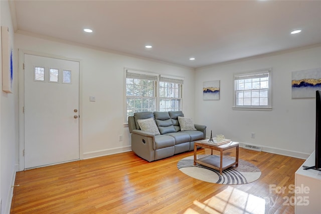 living room with ornamental molding, baseboards, and light wood finished floors