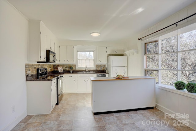 kitchen featuring range with electric cooktop, a sink, freestanding refrigerator, and white cabinets