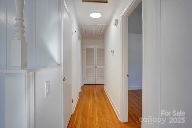 corridor featuring baseboards, attic access, and light wood-style floors