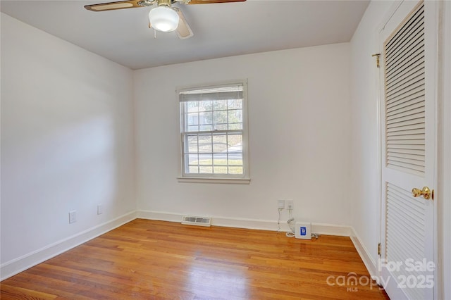 unfurnished room with visible vents, ceiling fan, baseboards, and wood finished floors