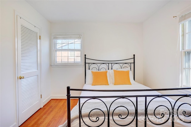 bedroom featuring light wood-style flooring, multiple windows, and baseboards