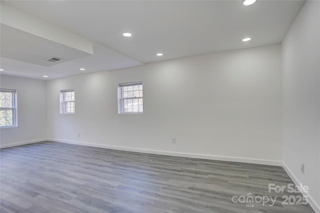 empty room featuring baseboards, visible vents, wood finished floors, and recessed lighting