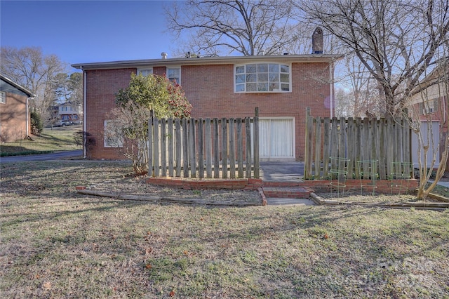 back of house featuring brick siding, a lawn, a chimney, and fence