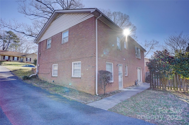 view of side of home with brick siding and fence