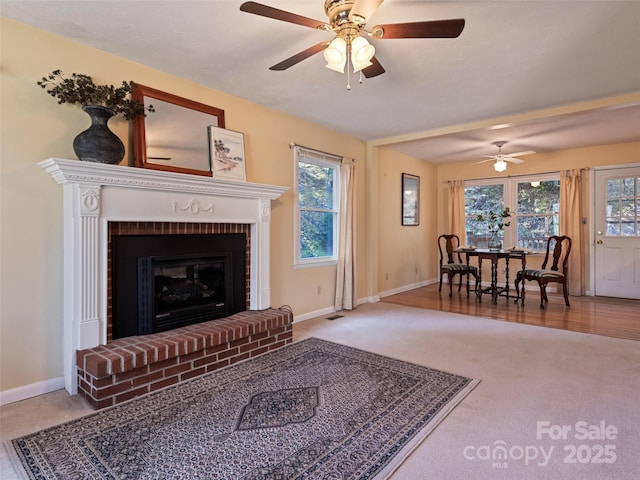 carpeted living room with a fireplace, baseboards, and ceiling fan