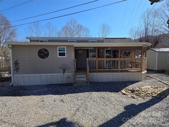 view of front of house with a storage shed, a porch, and an outdoor structure