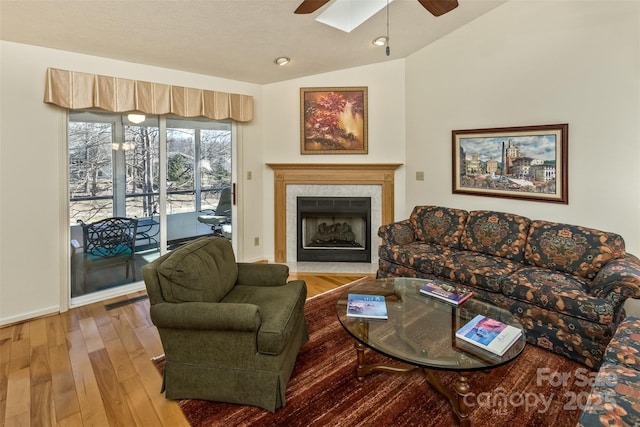 living room with visible vents, lofted ceiling, ceiling fan, a premium fireplace, and wood finished floors