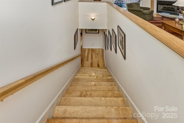 staircase with a fireplace and wood finished floors