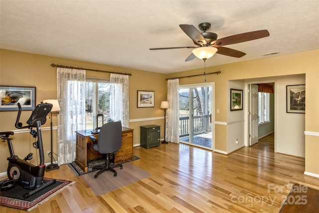 office with a wealth of natural light, visible vents, a textured ceiling, and light wood finished floors