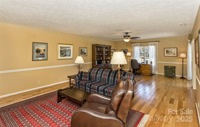 living room featuring a textured ceiling, baseboards, and wood finished floors