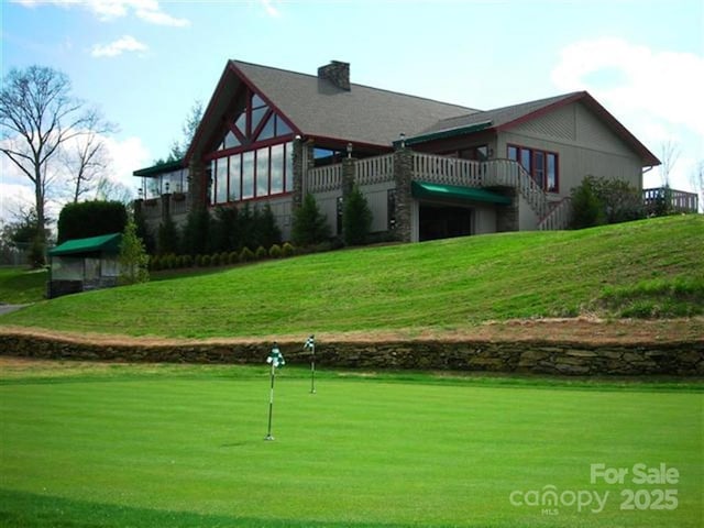 back of property with a chimney and a lawn