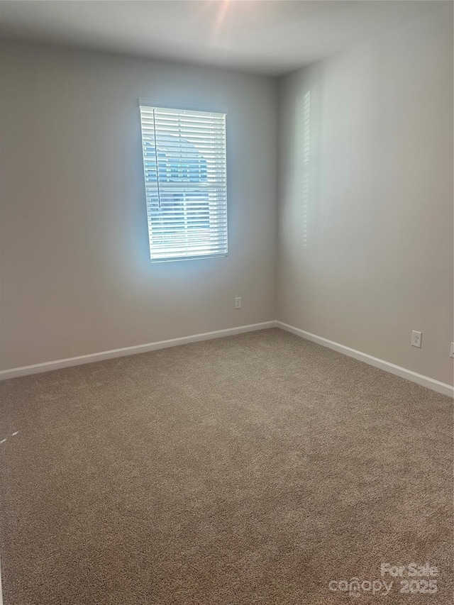 spare room featuring carpet flooring and baseboards