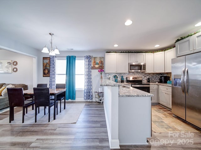 kitchen featuring appliances with stainless steel finishes, a sink, decorative light fixtures, and white cabinetry