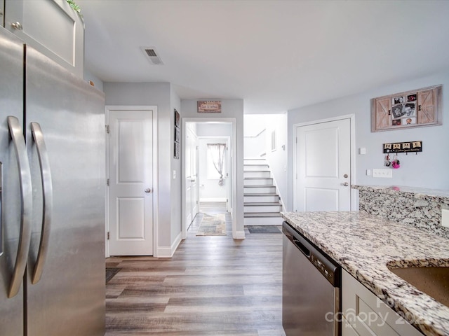 kitchen with light stone counters, wood finished floors, visible vents, baseboards, and appliances with stainless steel finishes