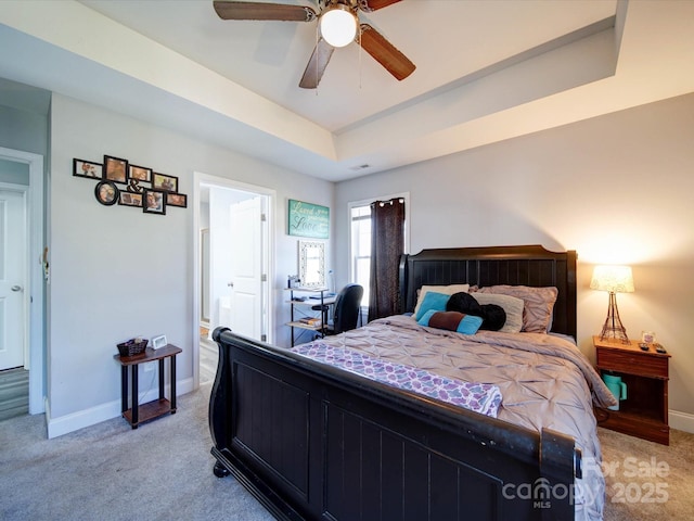 bedroom featuring baseboards, a tray ceiling, ceiling fan, and light colored carpet