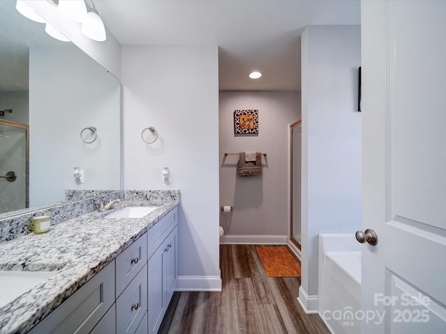 bathroom featuring a stall shower, baseboards, wood finished floors, and vanity