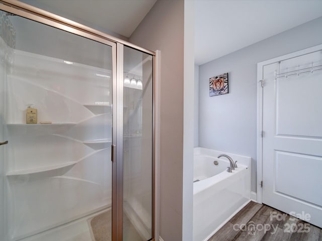 bathroom featuring a stall shower, wood finished floors, and a bath