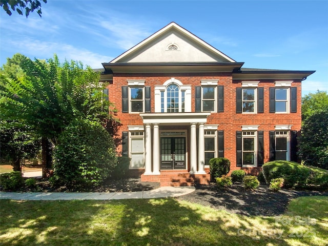 view of front of house featuring french doors, brick siding, and a front lawn