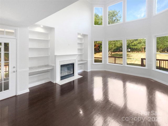 unfurnished living room with dark wood-type flooring, a fireplace with flush hearth, and baseboards