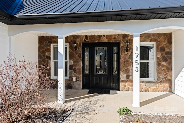 doorway to property with stone siding, metal roof, and a standing seam roof