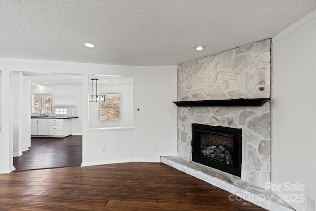 unfurnished living room with a textured ceiling, hardwood / wood-style floors, a fireplace, and baseboards