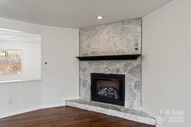 details with a textured ceiling, a fireplace, baseboards, and wood finished floors