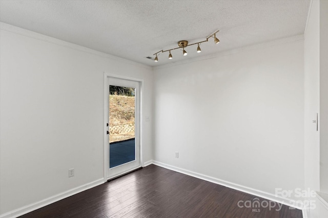 unfurnished room featuring ornamental molding, dark wood finished floors, a textured ceiling, and baseboards