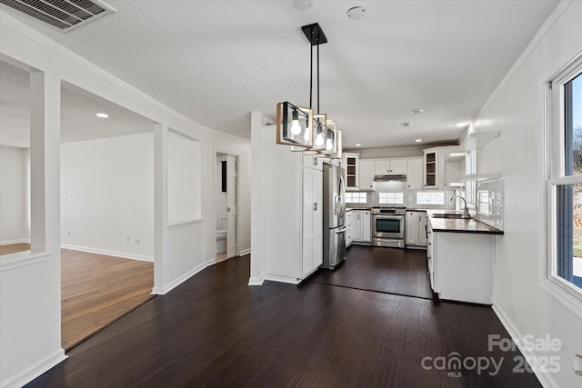 kitchen with appliances with stainless steel finishes, dark wood-type flooring, a sink, and white cabinets