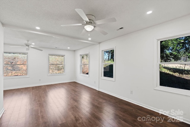 empty room with dark wood-style floors, visible vents, a textured ceiling, and baseboards