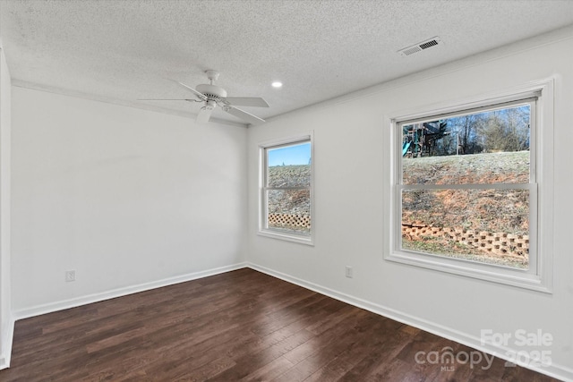 spare room featuring dark wood-style floors, visible vents, a ceiling fan, a textured ceiling, and baseboards