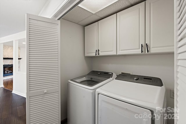 laundry area featuring cabinet space, a fireplace, dark wood-style floors, and washer and clothes dryer