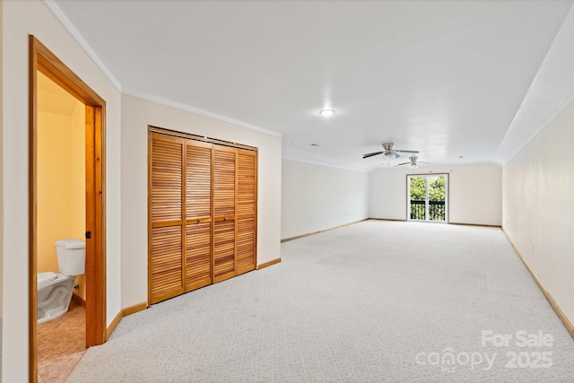 unfurnished bedroom with carpet, a closet, crown molding, and baseboards