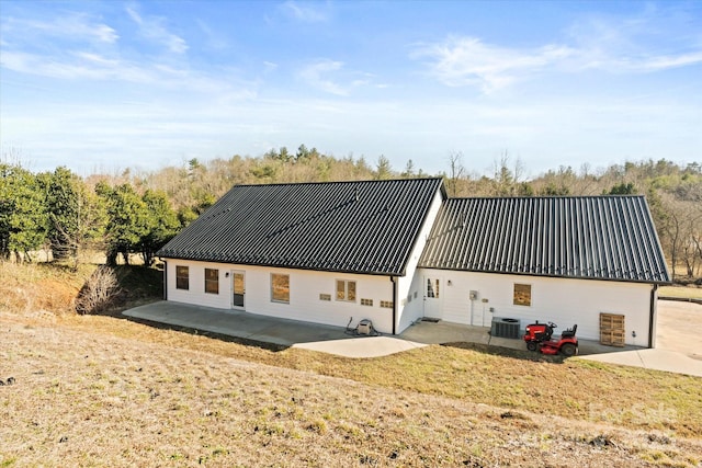 back of house with central air condition unit, metal roof, and a patio