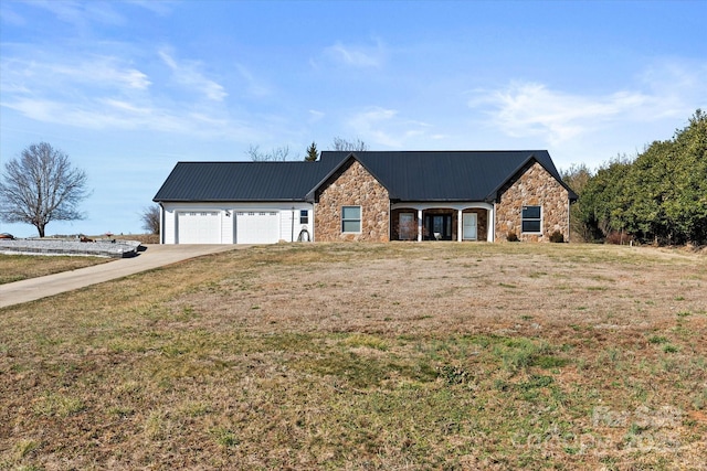 view of front of property featuring a garage, stone siding, and metal roof