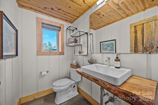 half bath featuring wooden ceiling, a sink, and toilet