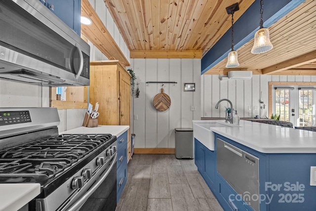 kitchen featuring hanging light fixtures, blue cabinetry, appliances with stainless steel finishes, and light countertops