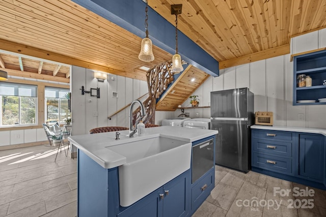 kitchen featuring blue cabinetry, washing machine and clothes dryer, freestanding refrigerator, and decorative light fixtures