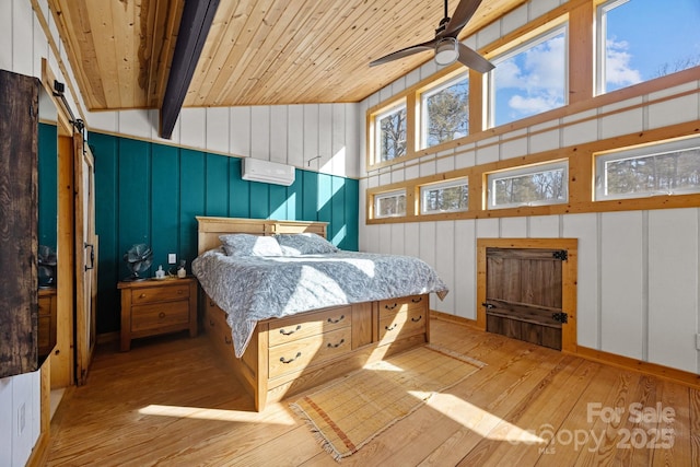 bedroom featuring a wall unit AC, vaulted ceiling with beams, light wood finished floors, a barn door, and wooden ceiling